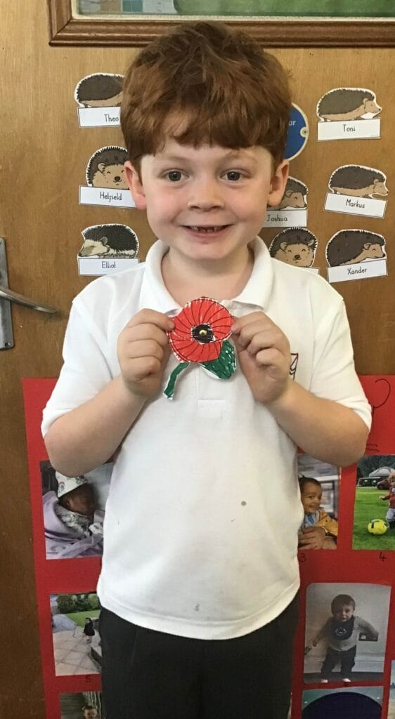 Young child holding a poppy drawing.