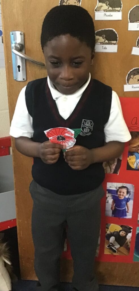 Young child holding a poppy drawing.