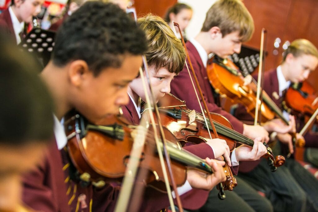 Wellingborough school musicians playing violins together in a lively performance.